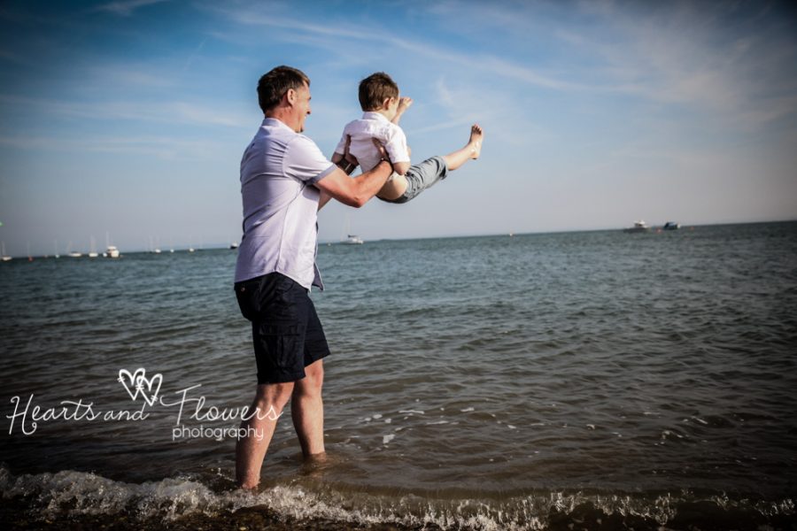 a daddy pretends to throw his little boy in the sea