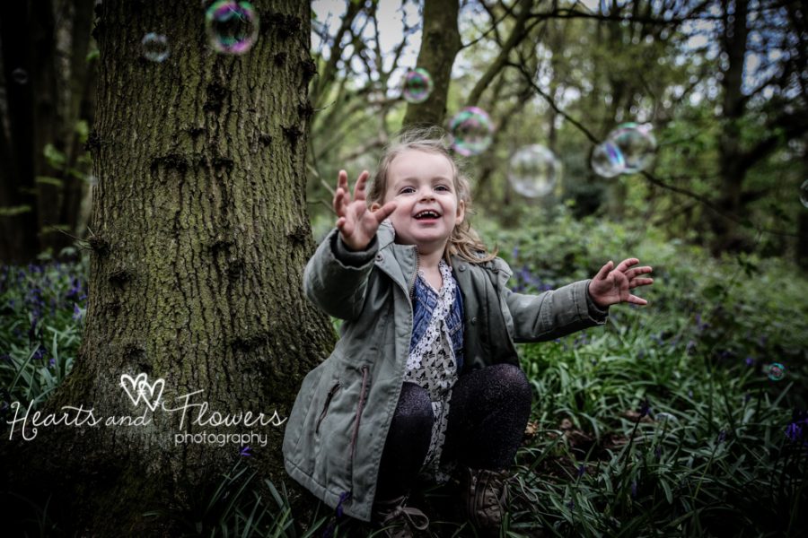 a little girl smiling as she plays with bubbles