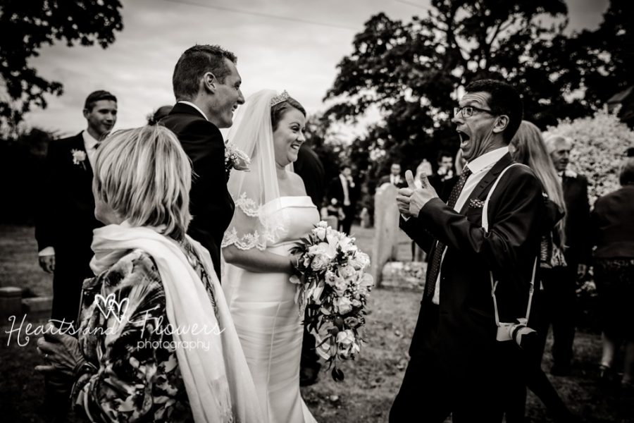 a funny wedding guest giving bride and groom a big thumbs up