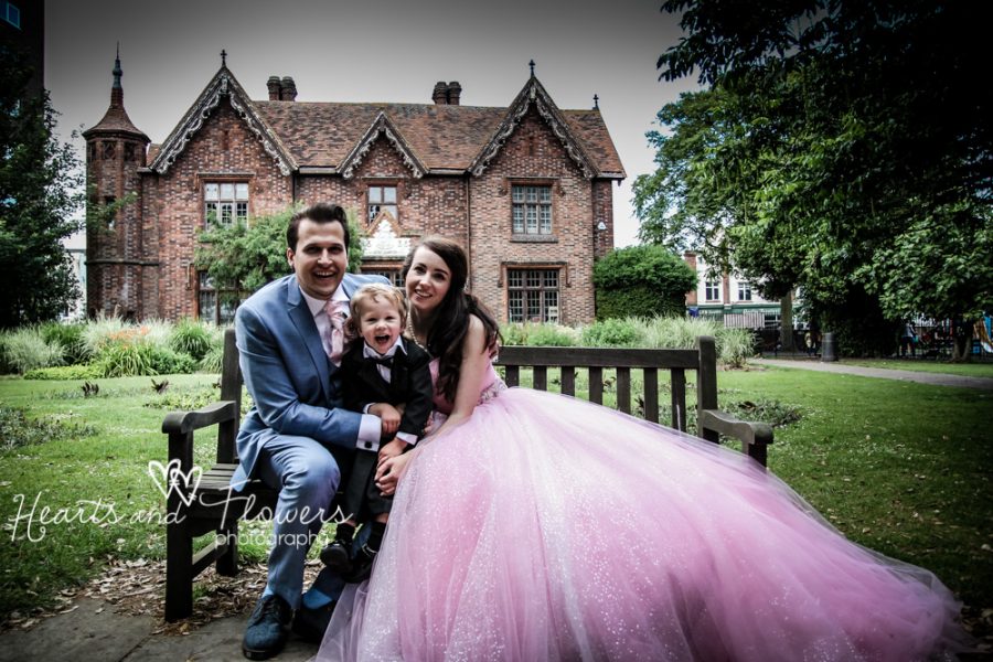 bride in a huge pink dress smiling with her husband and son