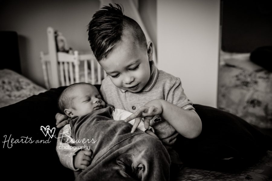 a little boy holding his baby brother in his arms