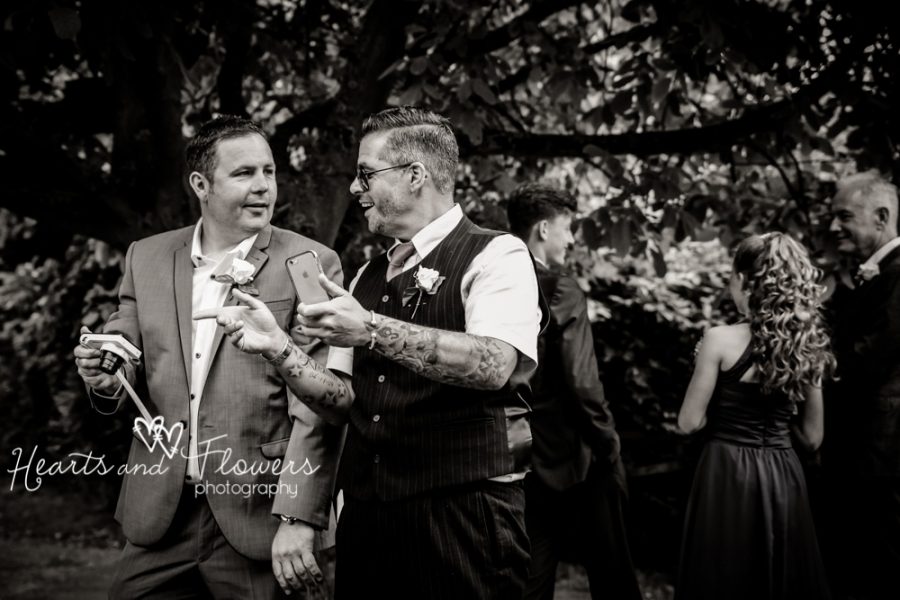 two male wedding guests bragging about their cameras and laughing