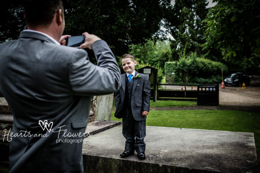 a wedding guest is taking a picture of his little boy in his suit