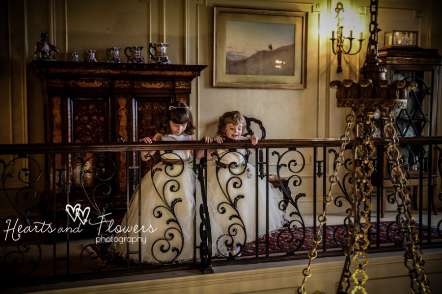 Two little flower girls are looking down over the top of the staircase