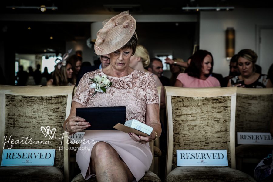 a posh lady at wedding sitting alone in a big hat