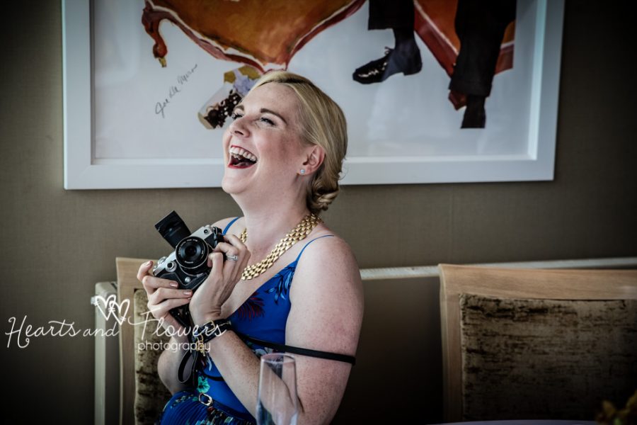 a lady is laughing at a wedding while she holds her vintage camera