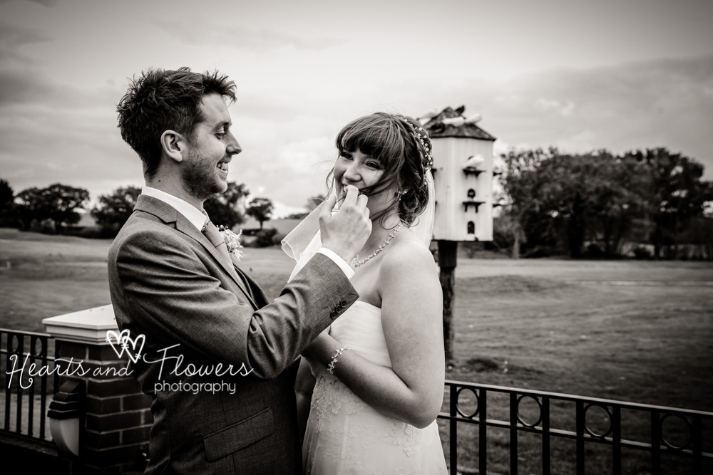 during pictures outdoors, a groom is taking hair out of his brides moth. it got blown there in the wind.